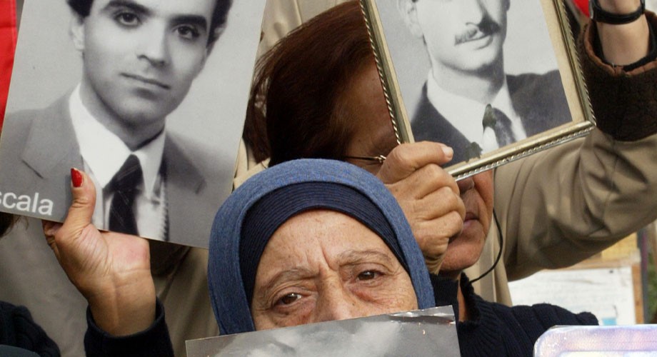 Mujer exhibe fotografías de víctimas del conflicto en Siria